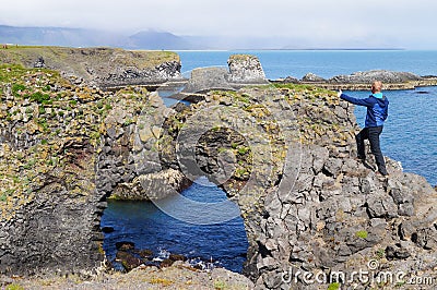 Unidentified tourist standing at Gatklettur Stone Arch,Iceland Editorial Stock Photo