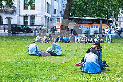 Unidentified tourists tourists resting on the grass near Westminster Abbey Editorial Stock Photo
