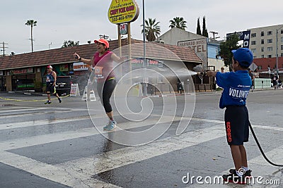 Unidentified volunteer boy throwing water in a runner Editorial Stock Photo
