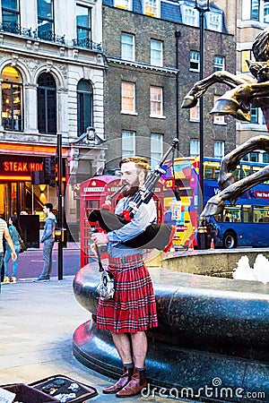 Unidentified young man with a bagpipe in the Scottish national dress at Piccadilly Circus Editorial Stock Photo