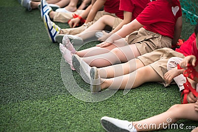 Uniformed children aligned legs sitting on grass Stock Photo