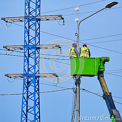 Uniformed electricians repairing electrical wires on a high pole Editorial Stock Photo