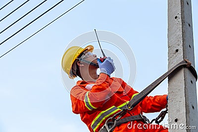 Uniformed electricians work on high-rise electricity poles along with safety equipment Stock Photo