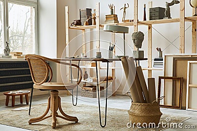 Unique artist workspace interior with stylish desk, wooden easel, bookcase, artworks, painting accessories, decoration. Stock Photo