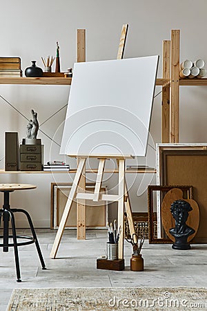 Unique artist workspace interior with wooden easel, bookcase, artworks, painting accessories, decoration. Stock Photo
