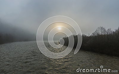 A unique dawn in the Carpathians with fog over a fast river. Stock Photo