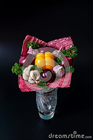 Unique festive bouquet of yellow peppers, red onions, garlic, mushrooms and parsley on a black background. Vegetable bouquet Stock Photo