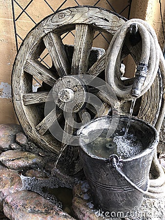 Unique Garden Fountain, Large Wagon Wheel, Bucket and Hose Stock Photo