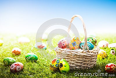 Unique hand painted Easter eggs in basket and lying on grass, blue sky Stock Photo