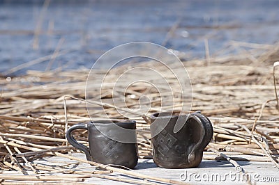 Unique handmade two cups with folk sign with blurred lake on background Stock Photo