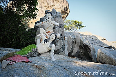 The mermaid sits on a rock and behind it a flute player Stock Photo