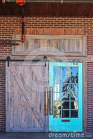 Unique rustic barn door entrance to building with reflection of nature in one side with glass panes all set in brick with red Stock Photo