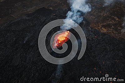 Erupted volcano and surroundings, boiling lava flowing, pull away drone shot Stock Photo