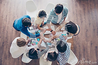 Unity and connection of people. Topview of partners putting their hands together, they sit at nice workstation, wearing casual cl Stock Photo