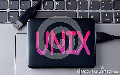 UNIX - acronym on an external drive in gray letters on the background of a laptop Stock Photo