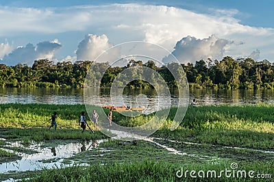 Unknown children play on the river bank, near the village. Sunset, end of day. June 26, 2012 in Village, New Guinea, Indonesia Editorial Stock Photo