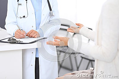 Unknown doctor and female patient discussing something while standing near reception desk in emergency hospit Stock Photo