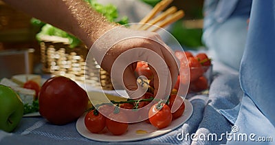 Unknown human hands take tomatoes on picnic closeup. Man arm hold red vegetables Stock Photo