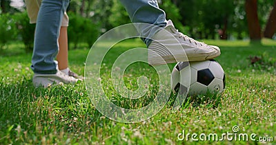 Unknown human legs kicking ball on grass closeup. Father play football with son. Stock Photo