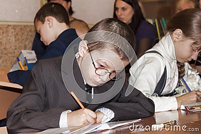 An unknown junior student at a desk writes something in a notebook at a lesson in one of the schools in Sloviansk Editorial Stock Photo