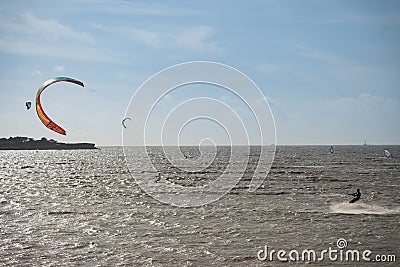 Unknown kitesurfers surf on brown water with waves from the Atlantic Ocean Stock Photo