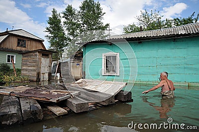 An unknown man on a flooded plot near his house. Editorial Stock Photo