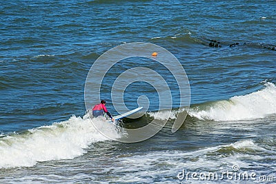 ZELENOGRADSK, KALININGRAD REGION, RUSSIA - JULY 29, 2017: Unknown surfer resting and having of surf on the blue waves. Editorial Stock Photo