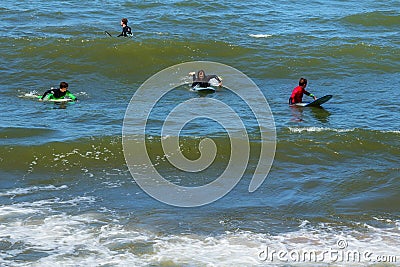 ZELENOGRADSK, KALININGRAD REGION, RUSSIA - JULY 29, 2017: Unknown surfers resting and having of surf on the blue waves. Editorial Stock Photo