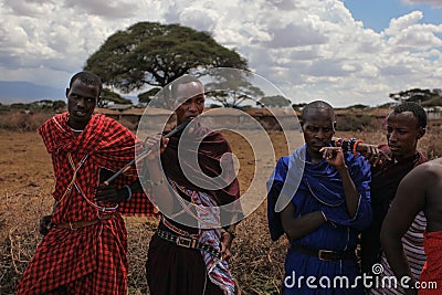 Unknown village near Amboselli park, Kenya - April 02, 2015: Unknown four Maasai warriors in traditional bright colored robes, ph Editorial Stock Photo