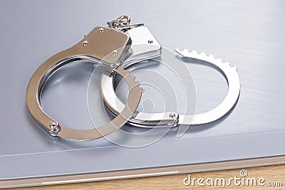 Unlocked pair of handcuffs on a closed laptop Stock Photo