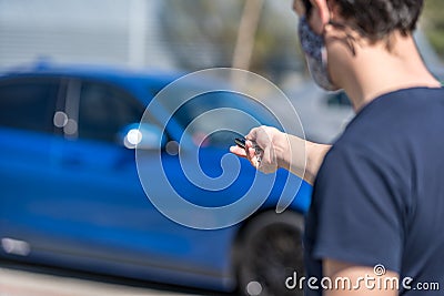 Unlocking a car by remote control. man in a medical mask at the time of the coronavirus epidemic Stock Photo