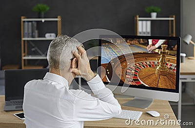 Unlucky gambler plays an online casino game on his computer and loses all his money Stock Photo