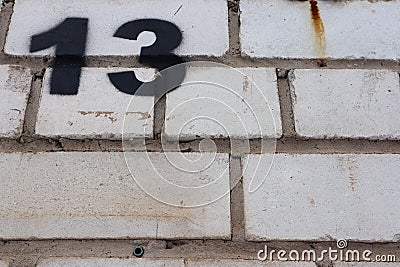 Unlucky unfortunate number thirteen painted black on a white brick wall Stock Photo