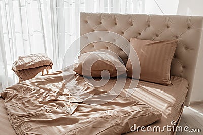 Unmade bed with crumpled bed sheet, a blanket and pillows after waking up in the morning. Close up view of hypoallergenic Cotton Stock Photo