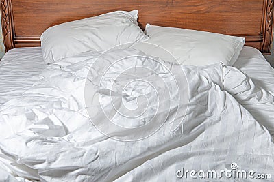 Unmade bed with white linens. Unmade empty bed. Close up of white sheets on bed Stock Photo