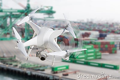 Unmanned Aircraft System Quadcopter Drone In The Air Near Large Shipping Vessel and Dock with Crates Stock Photo