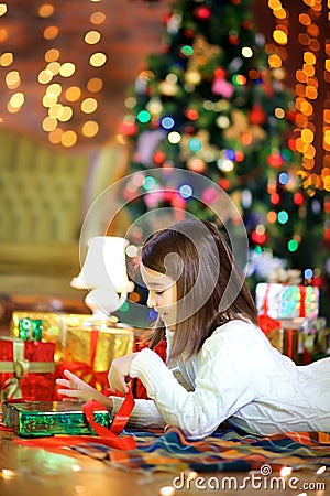 Unny girl lies on the floor and opens gifts Stock Photo