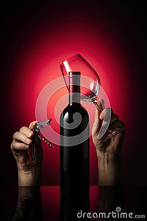 Unopened bottle of red wine and hands with corkscrew and wine glass Stock Photo