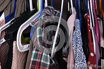Unorganized clothes of different colors hanging in a wardrobe in mess close up, storage and order at home, cleaning and Stock Photo