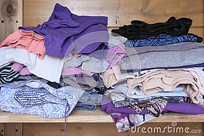 Unorganized heaps of clothes of different colors in a wardrobe lying in mess close up Stock Photo