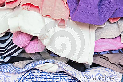 Unorganized heaps of clothes of different colors in a wardrobe lying in mess close up Stock Photo