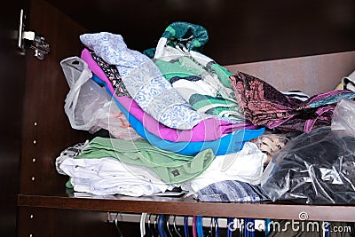 Unorganized heaps of clothes of different colors in a wardrobe lying in mess, storage and order at home Stock Photo