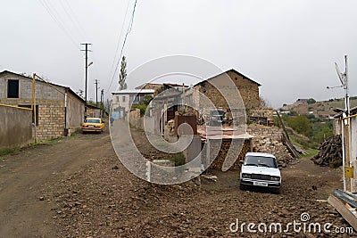 Unpaved street with cars and wooden storage for houses in the town of Hadrut part of the Janapar Trail in Nagorno Karabakh in the Editorial Stock Photo