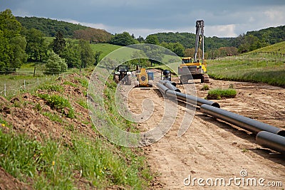 Unplugged gas pipeline in the coutryside diagonally from the right diagonally by photo with gas laying machines in the background Stock Photo