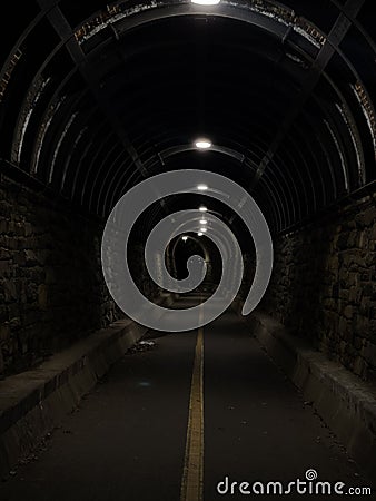 Unpopulated tunnel illuminated by light at night Stock Photo