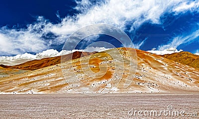 Unreal beautiful dry landscape, plain with dried salt lake plateau, colorful yellow red orange mountains, spectacular blue cloud Stock Photo