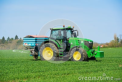 Tractor sprinkling fertiliser on wheat crop field. Hertfordshire. UK Editorial Stock Photo