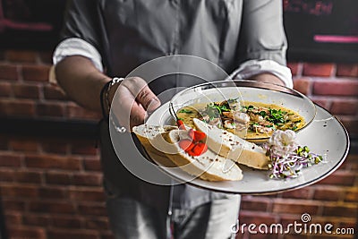 Unrecognisable waiter serving spicy chilli sauce shrimp dish with buttered bread. Restaurant service. Horizontal indoor Stock Photo