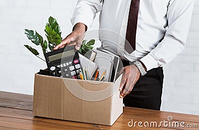 Unrecognizable black guy collecting his office stuff into carton box. Economic crisis and unemployment Stock Photo