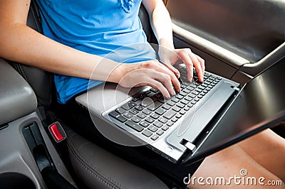 Unrecognizable businesswoman sitting in car with laptop computer on her knees Stock Photo